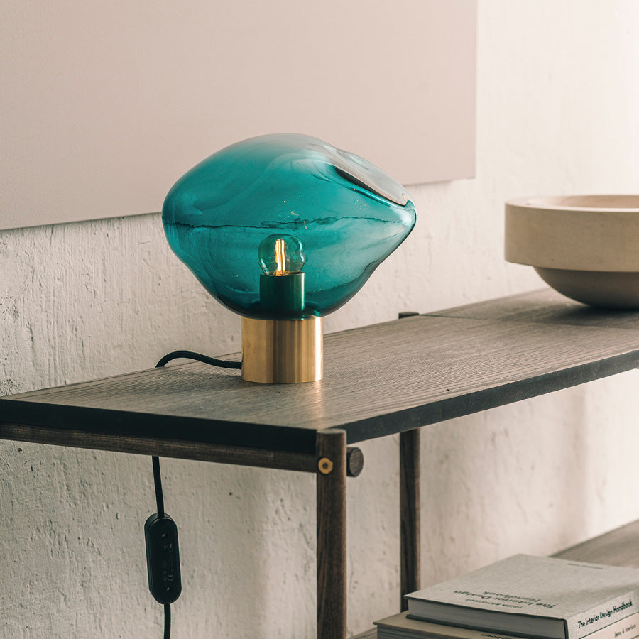 Crystal Stone bordlampe i fargen blågrønn fra Hadeland Glassverk. Bordlampen vises med messing fot.