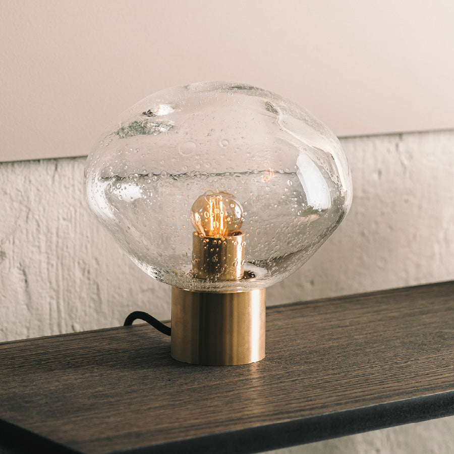 Nærbilde av Crystal Stone bordlampe i klar soda fra Hadeland Glassverk. Bordlampen vises med messing fot.