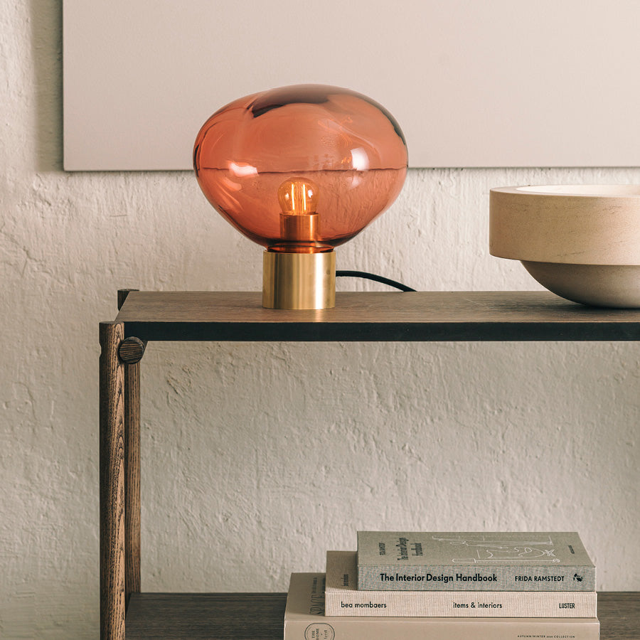 Crystal Stone bordlampe i fargen morgenrød fra Hadeland Glassverk. Bordlampen vises med messing fot.