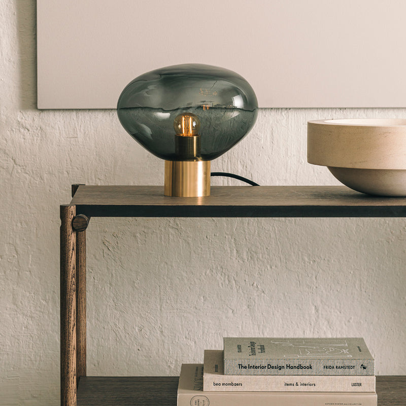 Crystal Stone bordlampe i fargen røkgrå fra Hadeland Glassverk. Bordlampen vises med messing fot.