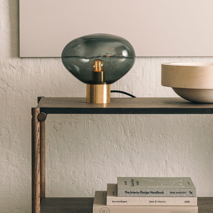 Crystal Stone bordlampe i fargen røkgrå fra Hadeland Glassverk. Bordlampen vises med messing fot.