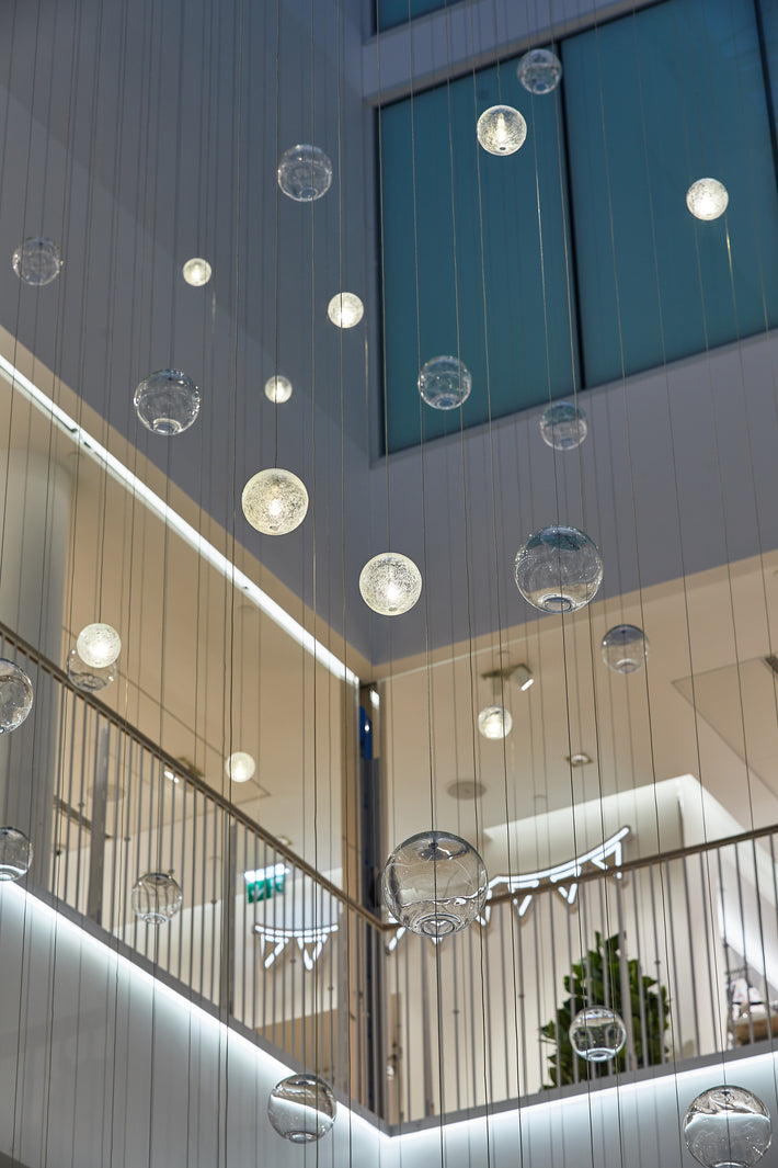 Munnblåste og håndslipte glasskuler fra Hadeland Glassverk utgjør lysinstallasjonen Gravity i H&Ms Flagship butikk i Karl Johan.