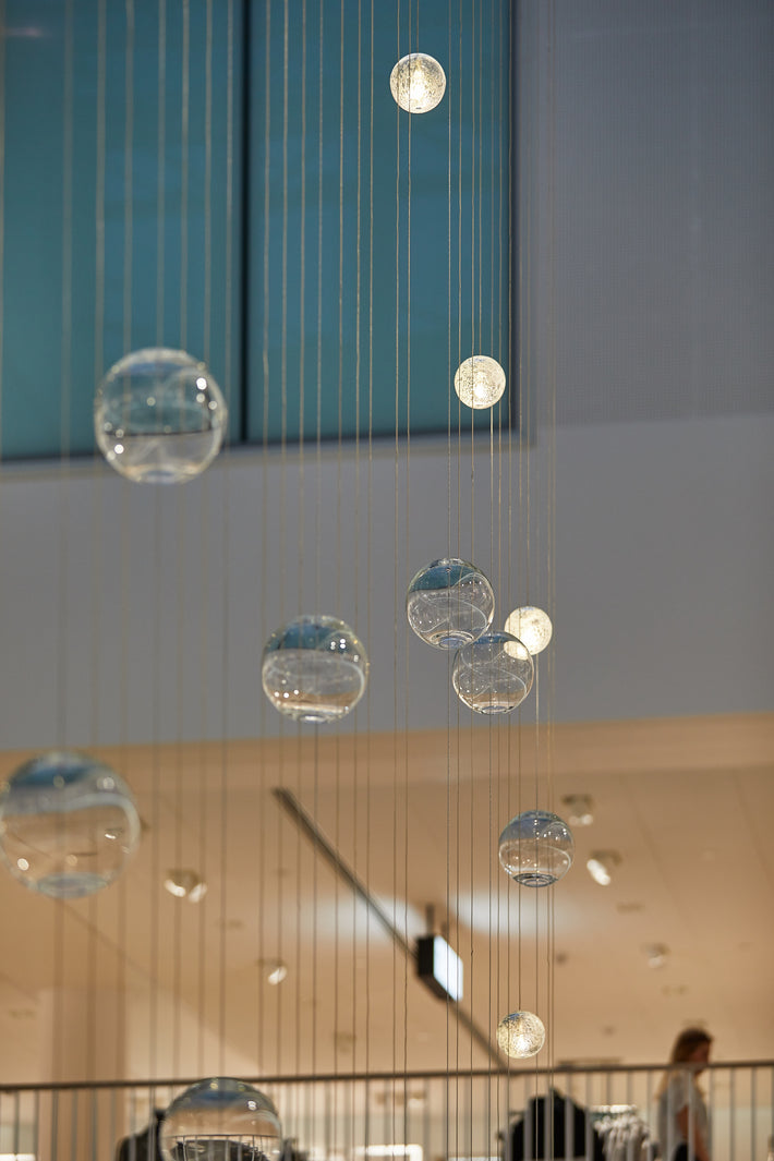 Munnblåste og håndslipte glasskuler fra Hadeland Glassverk utgjør lysinstallasjonen Gravity i H&Ms Flagship butikk i Karl Johan.
