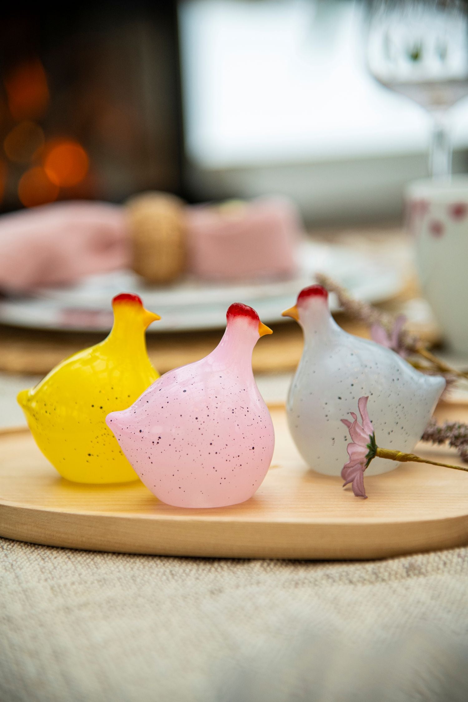 Glasshøner med gulldryss i fargene gul, rosa og hvit på et dekket påskebord