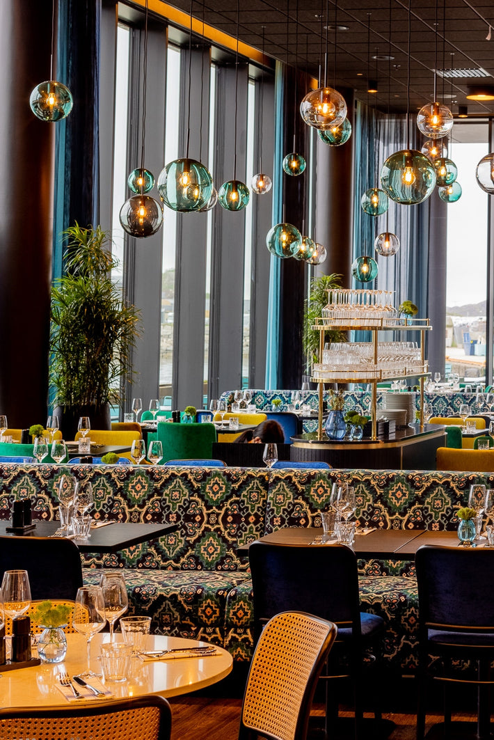 Prisbelønnet Arkiv 4014 pendellamper i ulike farger og størrelser fra Hadeland Glassverk i restauranten på Thon Hotel Svolvær.